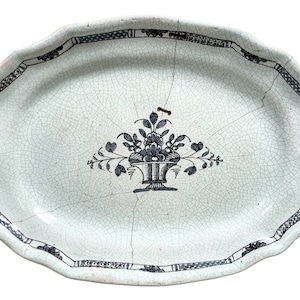 May include: An oval ceramic serving dish with a white glaze and a blue and white floral design. The dish has a scalloped edge and a crackled glaze.