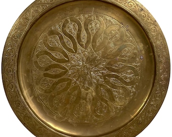 Puede incluir: Una bandeja redonda de latón de color dorado con un diseño intrincado en relieve. La bandeja tiene un borde elevado con un borde decorativo.