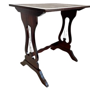 Könnte beinhalten: Ein dunkelbrauner Holz-Beistelltisch mit rechteckiger Tischplatte und Lyra-förmigen Beinen. Der Tisch hat ein schlichtes Design und ist aus massivem Holz gefertigt.