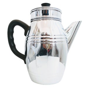 Może przedstawiać: Srebrny dzbanek do kawy z czarnym uchwytem i pokrywką. Dzbanek ma zaokrąglone ciało i dzióbek po boku.