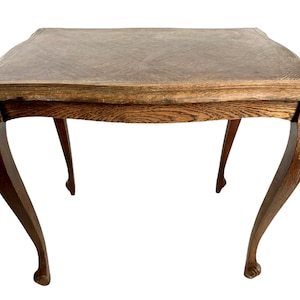 May include: A dark brown wooden table with a square top and four curved legs. The table has a simple design and is made of solid wood.