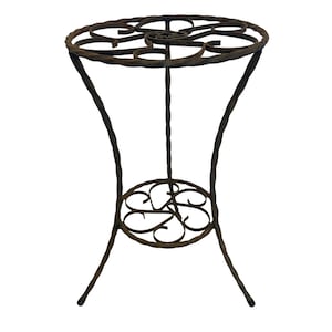 May include: A wrought iron plant stand with a round top and a lower shelf, both featuring decorative scrollwork. The stand has three curved legs and is finished in a dark brown color. The stand is approximately 24 inches tall.