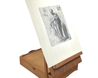 May include: A wooden easel with a drawer and a hinged top. The easel is holding a drawing of a person in a long robe.