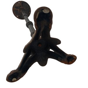 May include: A black cast iron table base with a three-legged design. The base has a circular top and a decorative, ornate design.