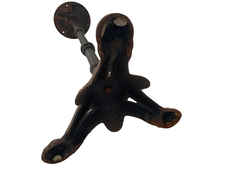 May include: A black cast iron table base with a three-legged design. The base has a circular top and a decorative, ornate design.