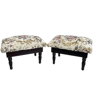 Puede incluir: Dos taburetes con estampado floral y patas de madera oscura. Los taburetes tienen un fondo crema con estampados florales marrones, rosas y azules.