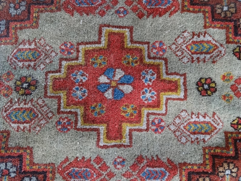 May include: A close-up of a colorful rug with a geometric pattern. The rug is made of wool and has a soft, textured surface. The colors in the rug are red, blue, yellow, and white.
