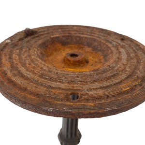 May include: A rusty metal bird bath with a circular top and a fluted base.