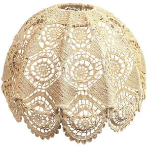 May include: A beige crocheted lampshade with a scalloped edge and a delicate floral pattern.