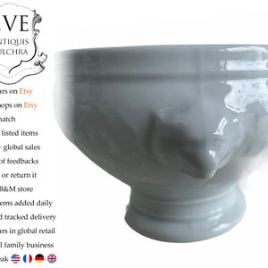 May include: White ceramic bowl with a unique, face-like design. The bowl has a rounded base and a wide, open top. The bowl is perfect for serving soup, salad, or other dishes.