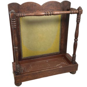 May include: A wooden coat rack with a padded back and a shelf underneath. The rack has a dark brown finish and features decorative details like turned spindles and a scalloped top.