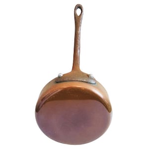 Puede incluir: Una pequeña cacerola de cobre con un mango largo. La cacerola tiene un acabado brillante ligeramente deslustrado.