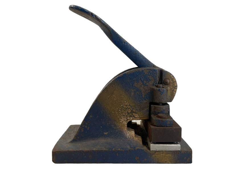 May include: A blue and gold metal hand-operated stamp with a lever. The stamp has a rectangular base and a lever that is attached to a metal plate.