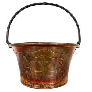 Può includere: Un secchio di rame con un manico in ferro battuto nero. Il secchio ha un design in rilievo con stelle e uno stendardo.