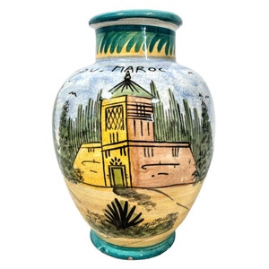Peut inclure: Un vase en céramique peint à la main avec une scène bleue, verte, jaune et orange d'un bâtiment avec un toit vert et des arbres. Le vase porte l'inscription "Du Maroc".