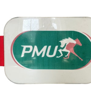 May include: A white rectangular sign with rounded corners featuring a green oval with a white horse and jockey in pink. The oval has a white outline and the text "PMU" in white letters.