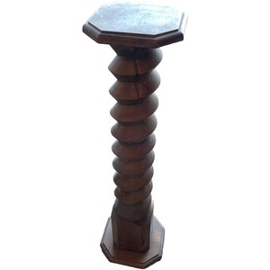 Peut inclure: Une table en bois avec un piédestal au design en spirale unique. La table a un plateau et une base hexagonaux.