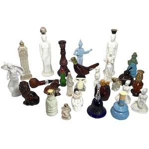 Op de afbeelding: Een verzameling van 20 miniatuur glazen parfumflesjes in verschillende vormen en kleuren. De flesjes zijn versierd met figuren, dieren en andere ontwerpen. Sommige flesjes zijn helder, terwijl andere ondoorzichtig zijn. De flesjes zijn gerangschikt op een witte achtergrond.