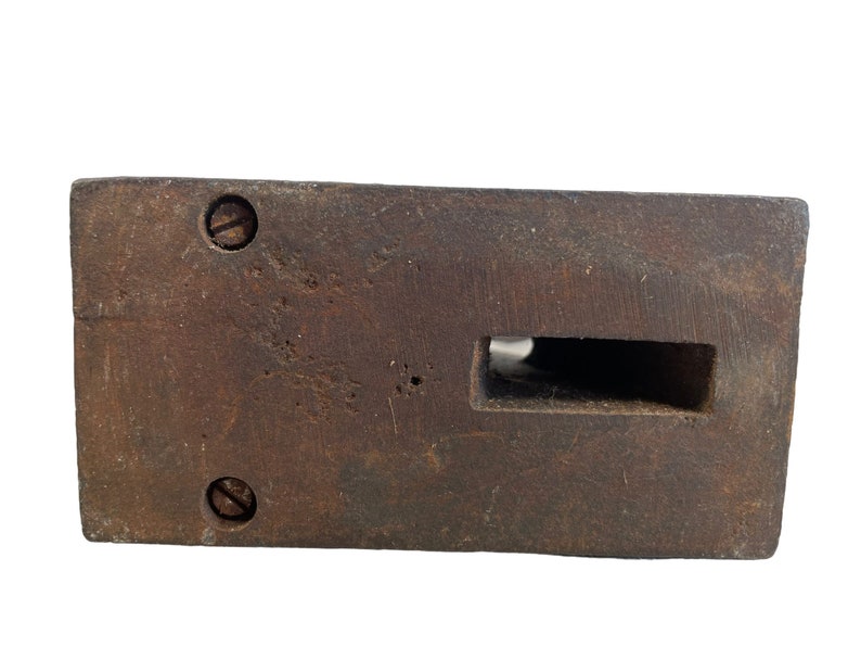 May include: A dark brown wooden block with a rectangular cutout and two visible screws. The block has a worn, rustic appearance.