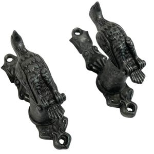 May include: A pair of silver metal curtain holdbacks in the shape of birds. The birds are perched on a decorative scroll design.