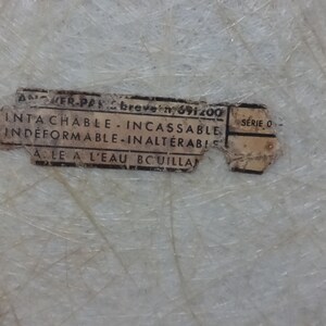 Puede incluir: Una etiqueta blanca con texto negro que dice "ANCHER-PAK breve n 691200 INTA CHABLE INCASSABLE INDEFORMABLE-INALTERABIL ALE A L'EAU BCUILLA SERIE O"