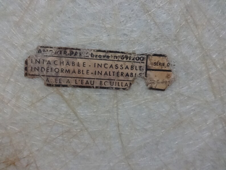 Puede incluir: Una etiqueta blanca con texto negro que dice "ANCHER-PAK breve n 691200 INTA CHABLE INCASSABLE INDEFORMABLE-INALTERABIL ALE A L'EAU BCUILLA SERIE O"