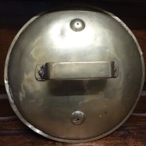 Peut inclure: Un couvercle rond en laiton avec une poignée. Le couvercle a une surface lisse et brillante et trois petits trous.