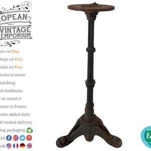 May include: A rustic, black cast iron bistro table stand with a round top and three legs. The stand has a decorative design on the legs and top.