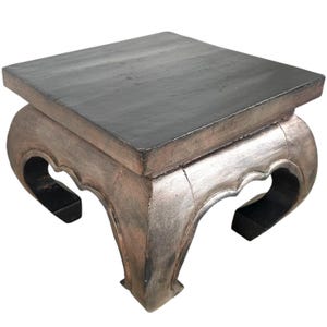 May include: A silver and black wooden end table with a square top and four legs. The legs are curved and have a decorative design.