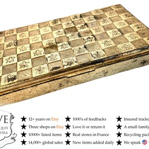 May include: A gold metal box with a checkered pattern and floral design. The box is closed and has a hinged lid. The box is made of metal and has a shiny finish.
