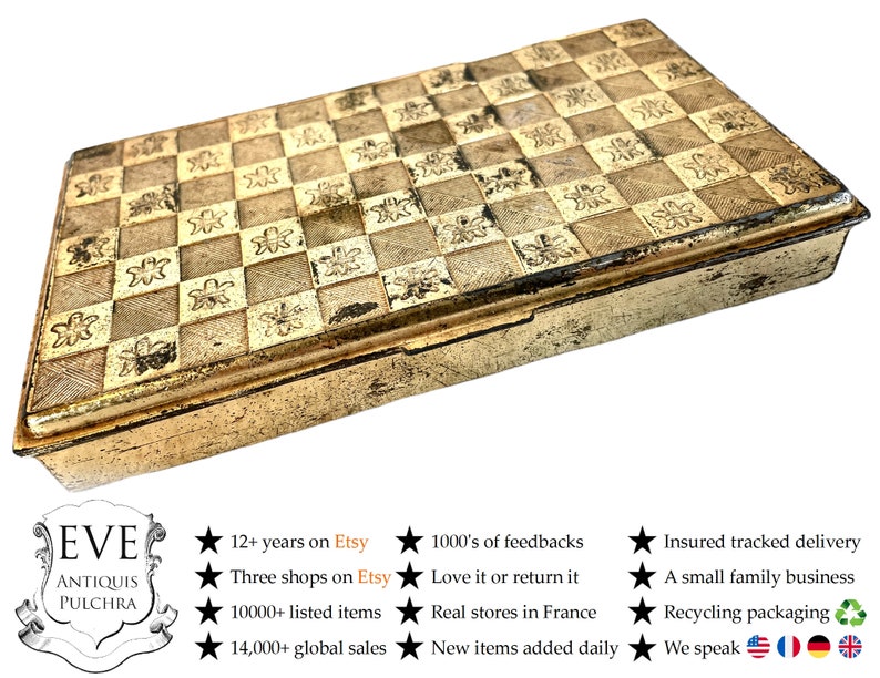 May include: A gold metal box with a checkered pattern and floral design. The box is closed and has a hinged lid. The box is made of metal and has a shiny finish.