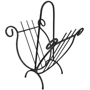 May include: Black metal magazine rack with a decorative, curved design. The rack features a lyre-like shape with vertical bars for holding magazines and a handle. The base has three curved legs and the top has decorative swirls.