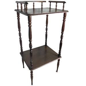 Puede incluir: Una mesa auxiliar de madera de color marrón oscuro de dos niveles con patas torneadas y un diseño sencillo.