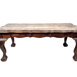 May include: A dark brown wooden coffee table with a scalloped edge and four carved legs.