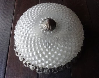 May include: Vintage ceiling light fixture with a clear, textured glass shade. The shade has a bubble pattern and is topped with a decorative metal cap. The fixture has a decorative metal trim around the base.