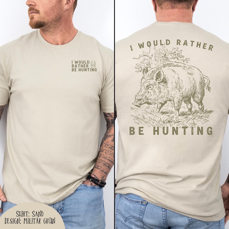 May include: Sand-colored t-shirt with the text "I WOULD RATHER BE HUNTING" on the front and a detailed illustration of a boar on the back. The shirt's design includes the text "SHIRT: SAND DESIGN: MILIT&Auml;R GR&Uuml;N".