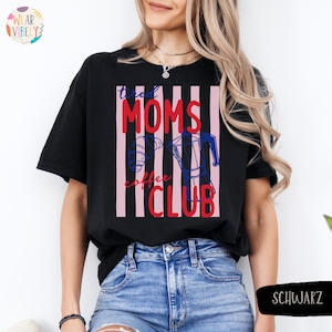 Pode incluir: Camiseta preta com a frase "tired MOMS coffee CLUB" em vermelho e branco, com um desenho de cafeteira. O design est&aacute; sobre um fundo de listras verticais rosa e brancas. A camiseta &eacute; usada com jeans azuis.