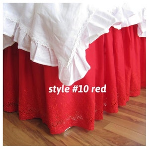 May include: Red bed skirt with white lace trim and embroidered details. The skirt is labeled "style #10 red".
