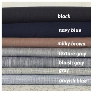 May include: A stack of fabric swatches in various shades of gray, blue, and brown. The swatches are labeled with the following colors: black, navy blue, milky brown, texture gray, bluish gray, gray, and grayish blue.