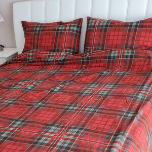 May include: Red and green plaid bedding with a white headboard. The bedding is made of a soft, comfortable fabric and has a classic plaid pattern.