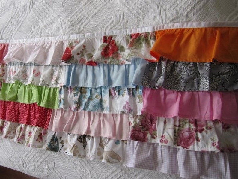 May include: A multi-colored ruffled fabric trim with a variety of floral patterns, including pink, green, blue, red, and white.