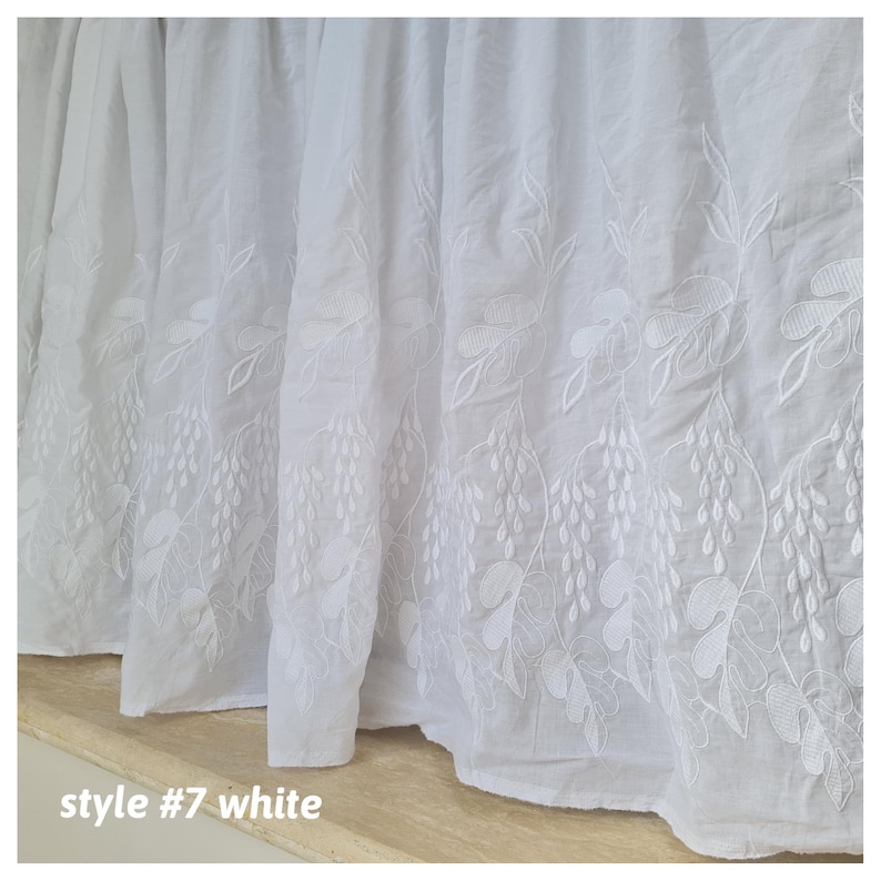 May include: White cotton bed skirt with an embroidered floral design. The skirt has a ruffled edge and is labeled "style #7 white".