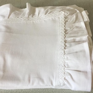 May include: White cotton bed sheet with a lace trim and ruffled edges.