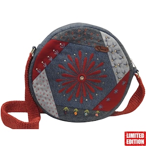 Könnte beinhalten: Runde Patchwork-Umhängetasche mit rotem Riemen. Die Tasche hat ein zentrales rotes Stickdesign, umgeben von grauen, roten und blauen Stoffflicken. Verziert mit kleinen Perlen und Stickereien. Die Tasche hat ein "Limited Edition"-Etikett.