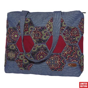 Könnte beinhalten: Eine Denim-Tragetasche mit Patchwork-Design. Die Tasche hat eine blaue Denim-Basis mit sechseckigen Patches in Burgunderrot und gemustertem Stoff. Die Tasche hat zwei Griffe und ein kleines Lederetikett mit einem Logo.