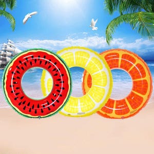 May include: Three inflatable pool floats in the shape of fruit: a watermelon, a lemon, and an orange. The watermelon float is red with black seeds and a green border. The lemon float is yellow, and the orange float is orange with white segments.