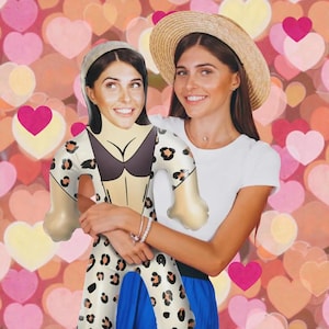 Könnte beinhalten: Eine Frau umarmt eine aufblasbare Puppe in einem Badeanzug mit Leopardenmuster. Das Gesicht der Puppe ähnelt dem der Frau. Die Frau trägt ein weißes T-Shirt, einen blauen Rock und einen Strohhut. Der Hintergrund ist ein Muster aus Herzen.