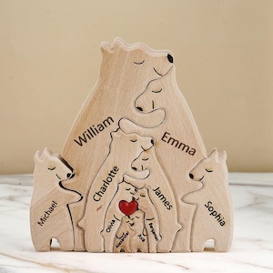 May include: A wooden family bear puzzle with the names William, Emma, Michael, Sophia, Charlotte, James, Olivia, Alexander, Benjamin, and Ava. The puzzle features a red heart and is made of light-colored wood.