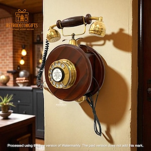 Puede incluir: Teléfono de pared vintage con acabado en madera oscura y detalles en latón. El dial rotatorio y el auricular son dorados. El teléfono está montado en una pared beige, un elemento clásico de decoración del hogar.