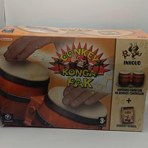 Puede incluir: Un juego de controlador DK Bongos de Nintendo GameCube en caja. La caja presenta un diseño vibrante con el texto "Donkey Konga Pak" e ilustraciones de bongos y el personaje Donkey Kong. La caja es naranja y marrón.